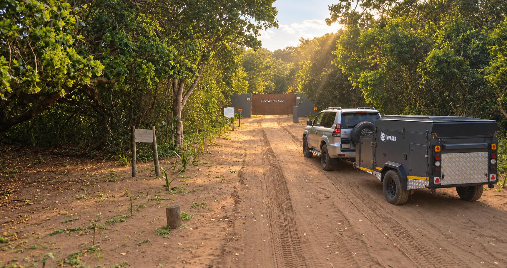 Four-wheel-drive vehicle and camping trailer approaching the Tierras del Mar gate